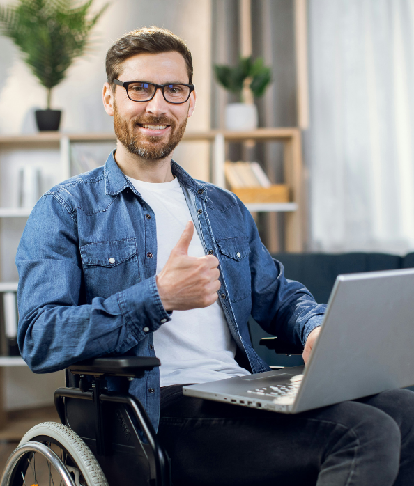 Man in wheelchair giving a thumbs up as he works on his laptop