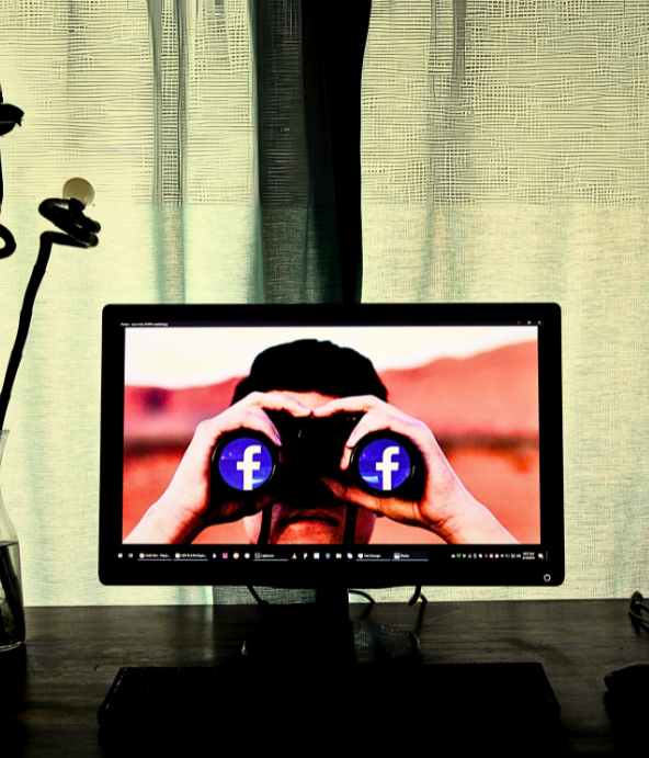 Computer screen showing a man with binoculars with the facebook logo on each lens