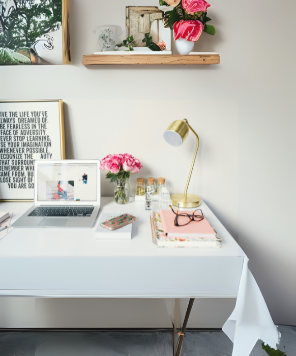 A highly feminine desktop with a small laptop among other more decorative items