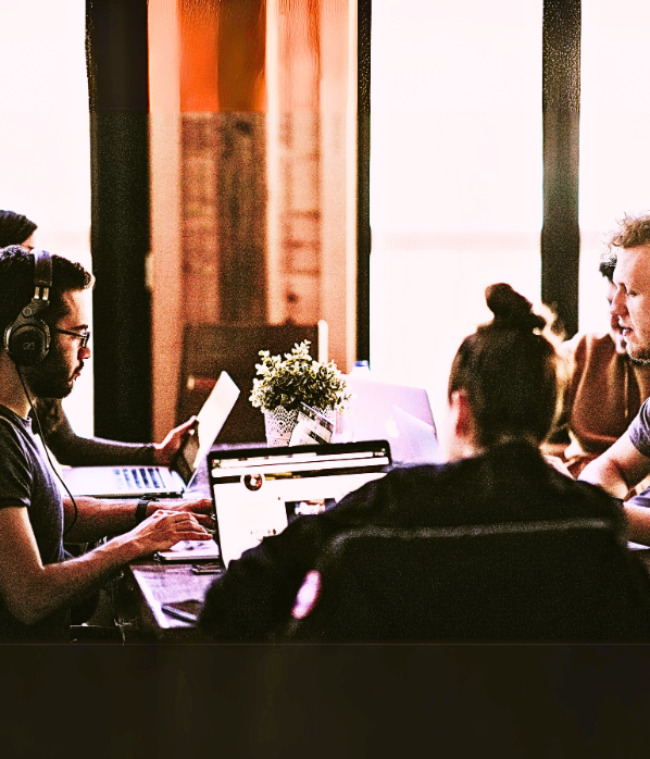 A coworking team sitting around a table looking at their laptops.