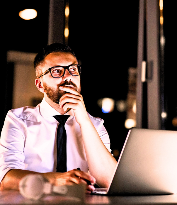 Man thoughtfully looking into space while sitting at a computer