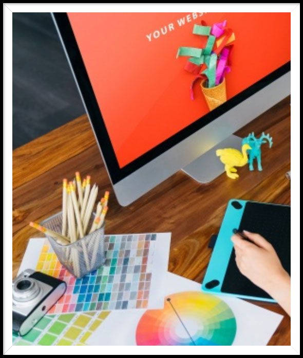 A computer with a bright color on the screen and a color wheel on the table in front of it.