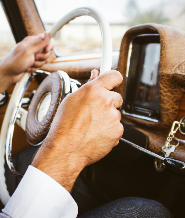 Man gripping the steering wheel of a classic 1950s car